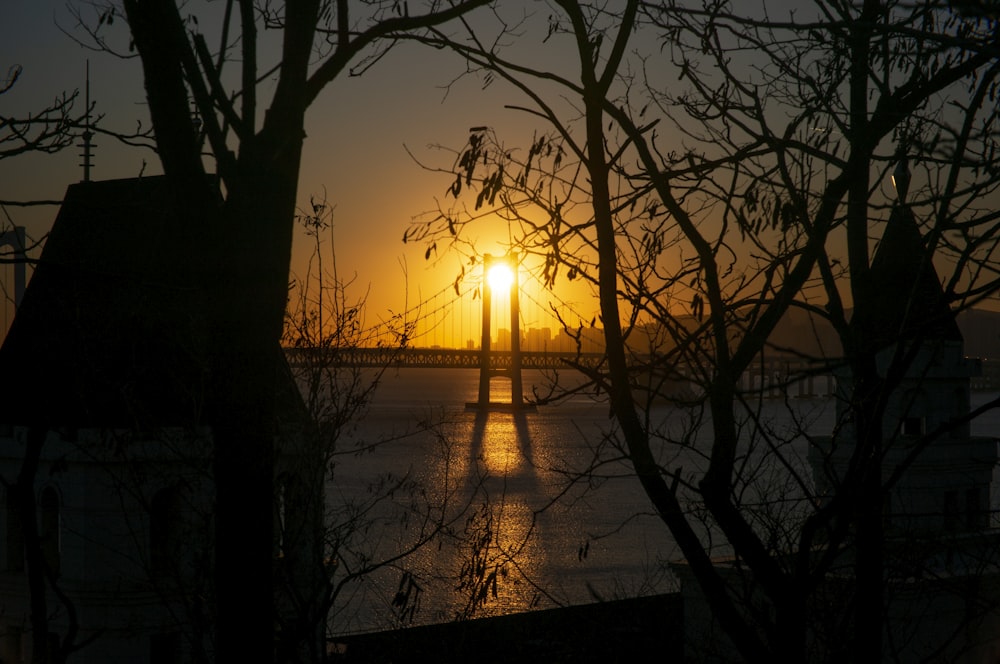 o sol está se pondo sobre uma ponte sobre um corpo de água
