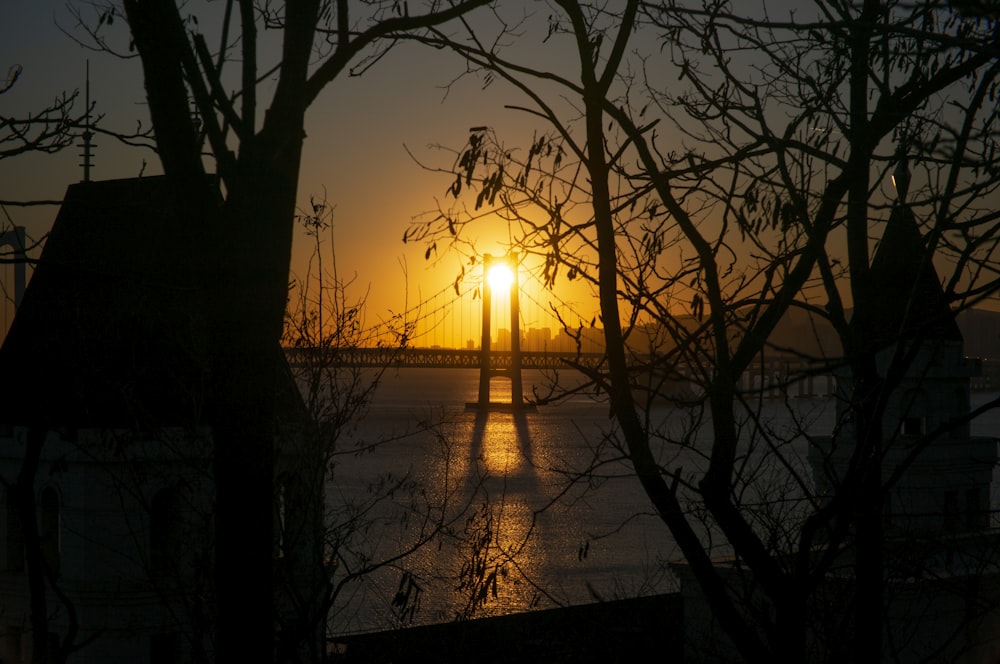 the sun is setting over a bridge over a body of water