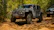 Close-up of a rugged off-road vehicle equipped with Neff Motorsports parts, kicking up dirt on a forest trail.