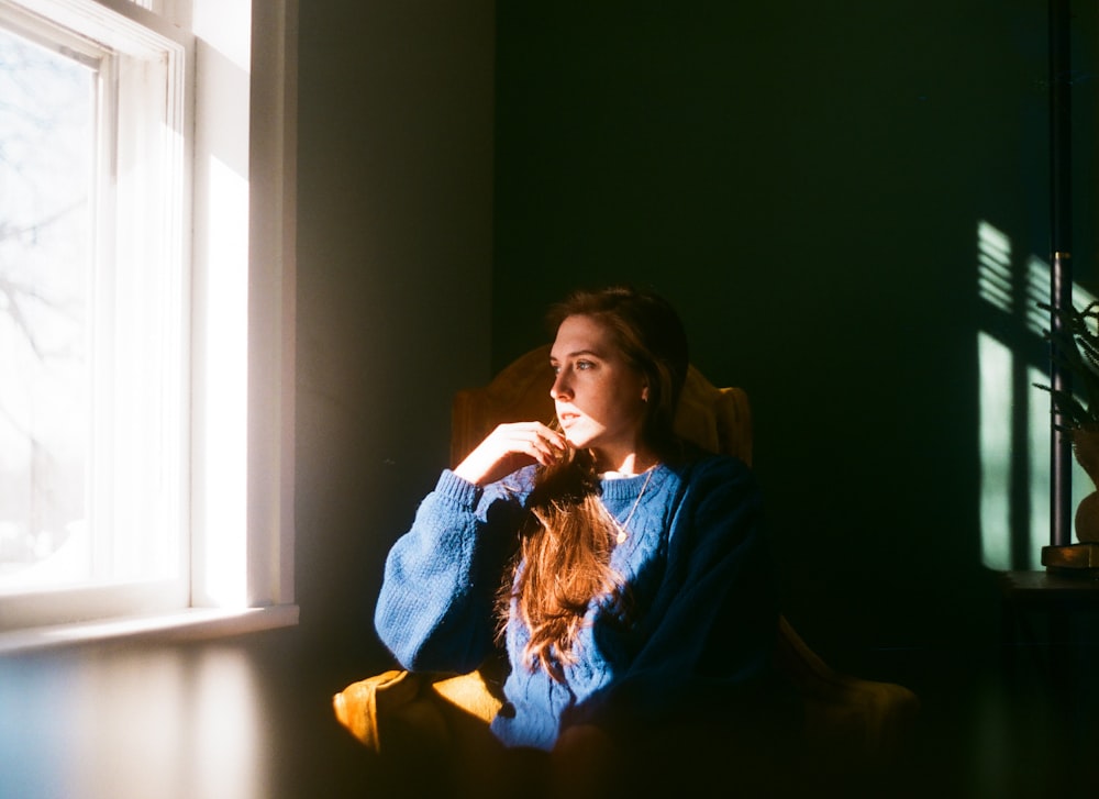 a woman sitting in a chair looking out a window