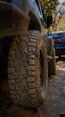 Close-up of a jeep tire gripping rocky terrain covered with moss and leaves.