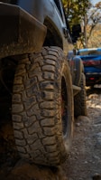 Close-up of muddy tires on a rocky path with green hills in the background