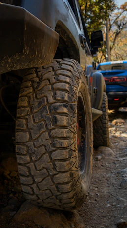 Close-up of rugged off-road tires gripping rocky terrain, dust swirling around.