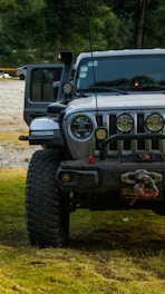 A skilled operator using winches to recover a car stuck off-road in a forested area.