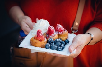A smiling person holding a plate full of freshly made brigadeiros