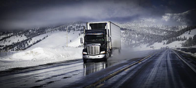 A NordLynx truck driving along a scenic Canadian highway surrounded by forests and mountains.