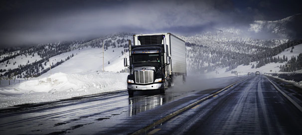 A Nordlynx truck rolling through a scenic Canadian highway surrounded by dense forests and mountains.