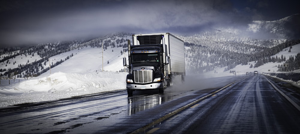 a semi truck driving down a snow covered road