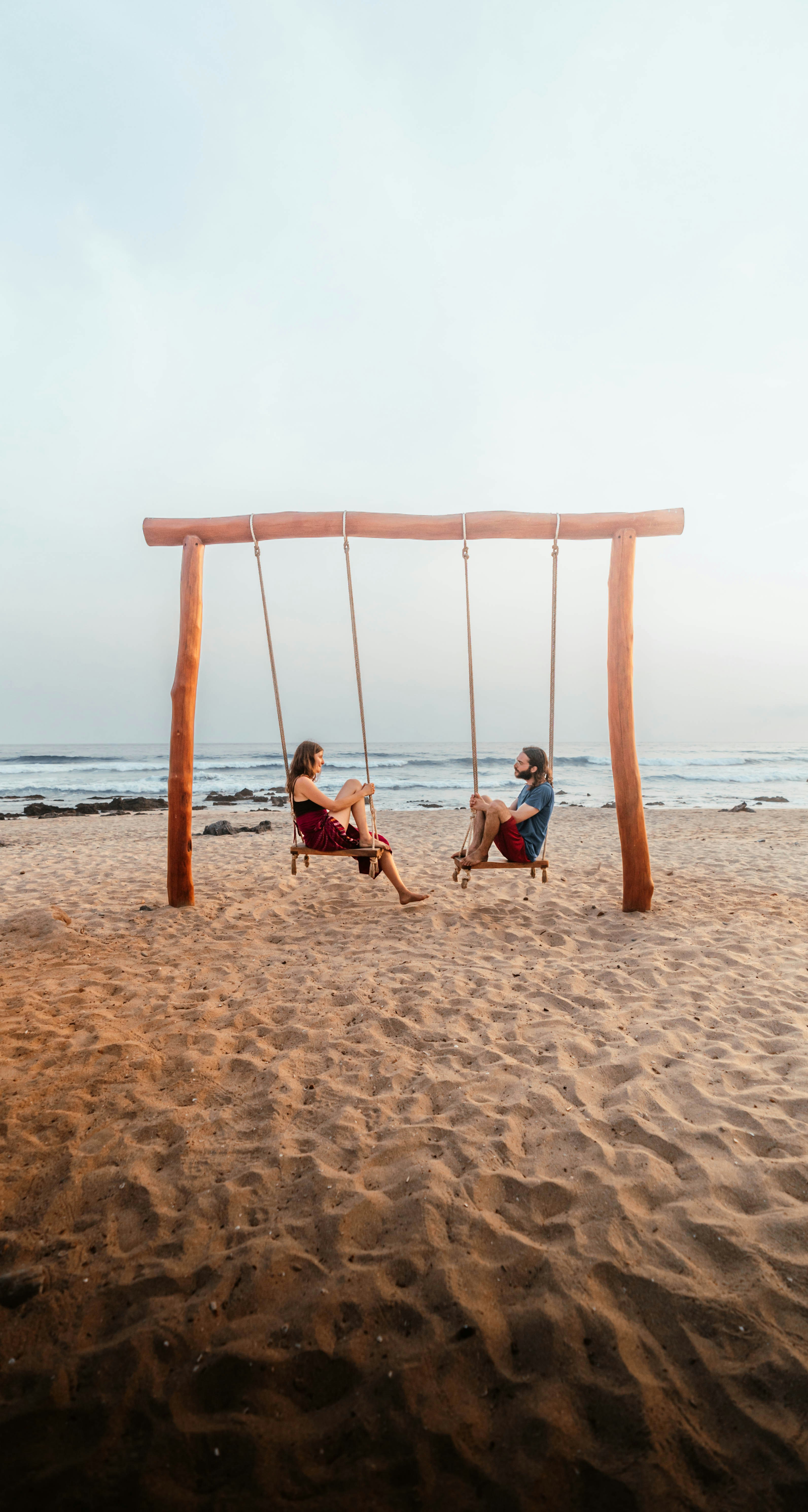 a couple of people sitting on top of a sandy beach