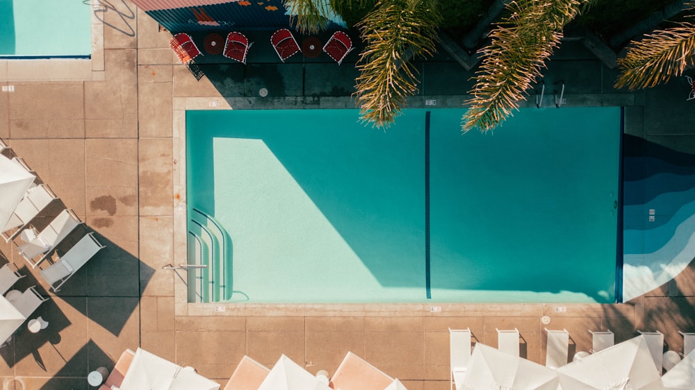 an overhead view of a pool with chairs and umbrellas