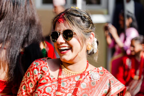 A joyful customer wearing a bright red pattu saree, smiling in a sunlit courtyard.