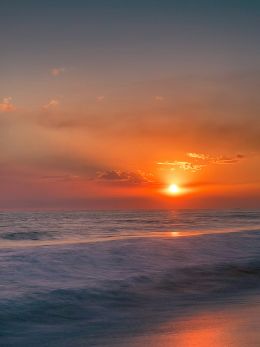 the sun is setting over the ocean on the beach