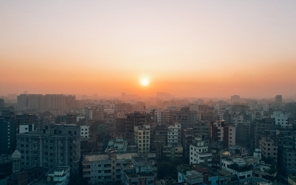 the sun is setting over a city with tall buildings