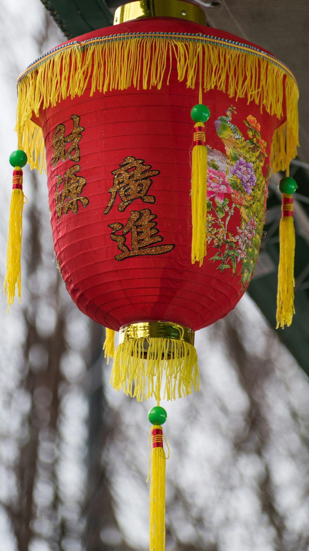 Une lanterne chinoise rouge avec des glands jaunes qui y pendent