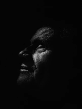 Black and white portrait of an elderly person with expressive eyes and gentle wrinkles.