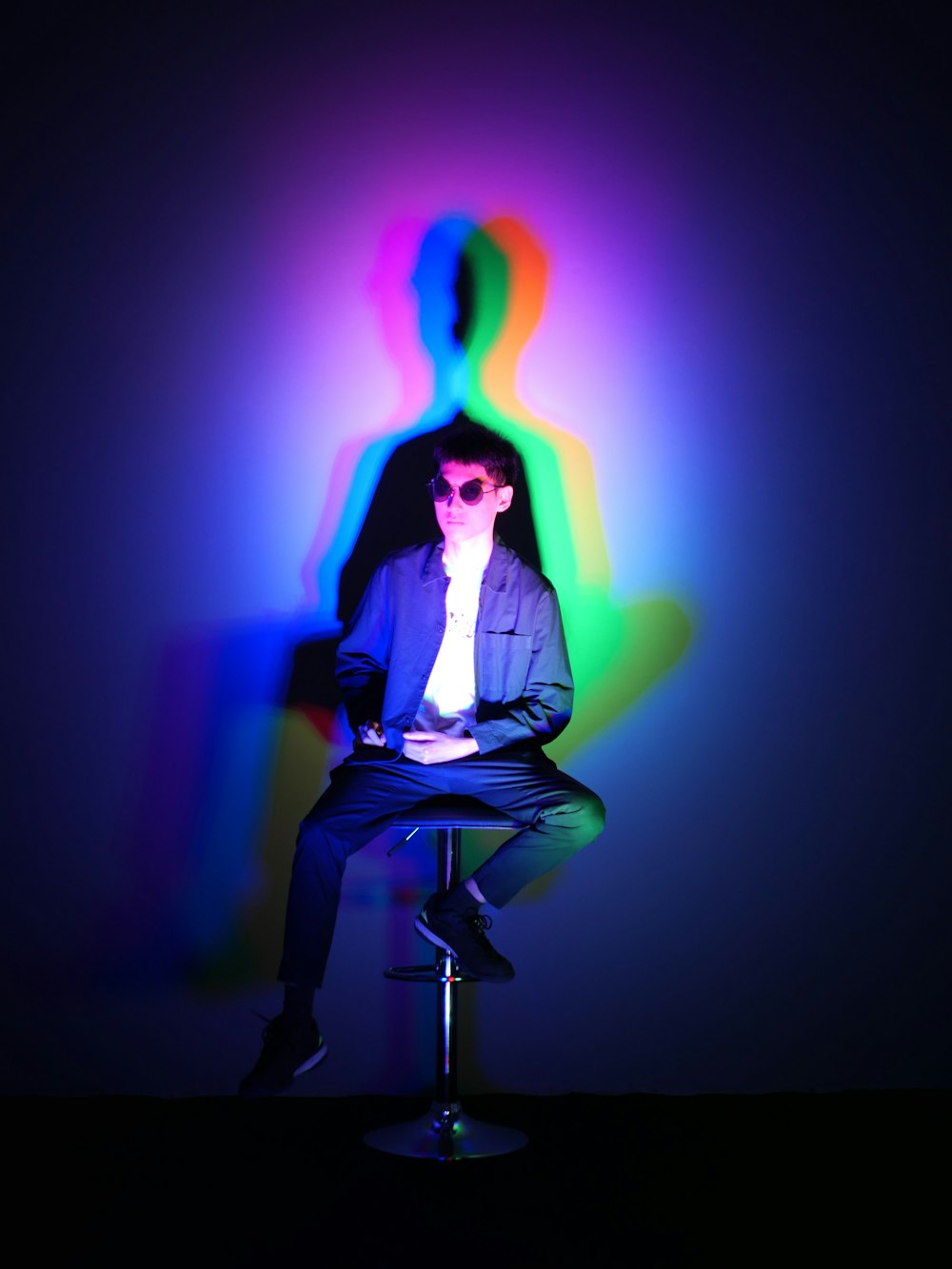 a man sitting on a stool in front of a colorful light