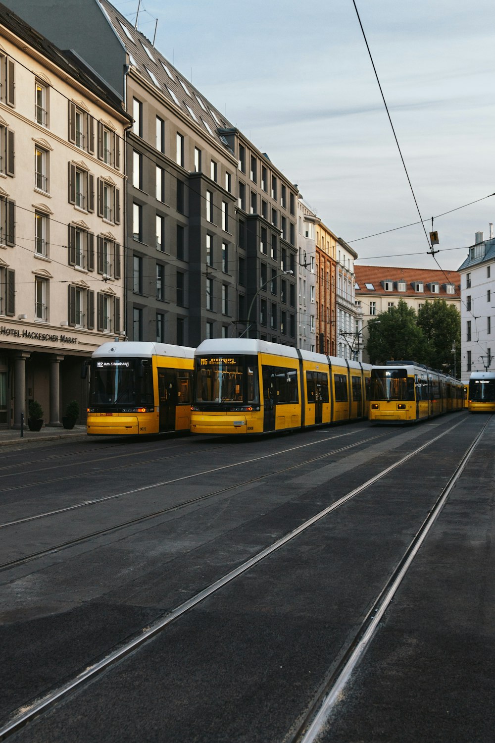 a yellow and white train traveling down a street next to tall buildings