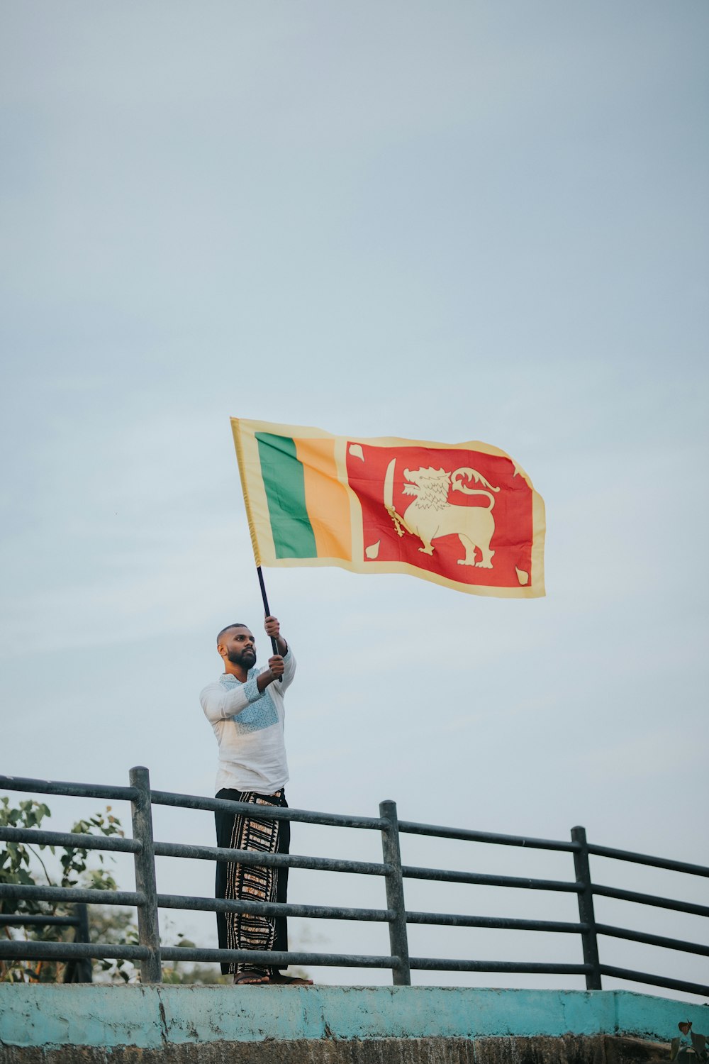 a man holding a flag on top of a bridge