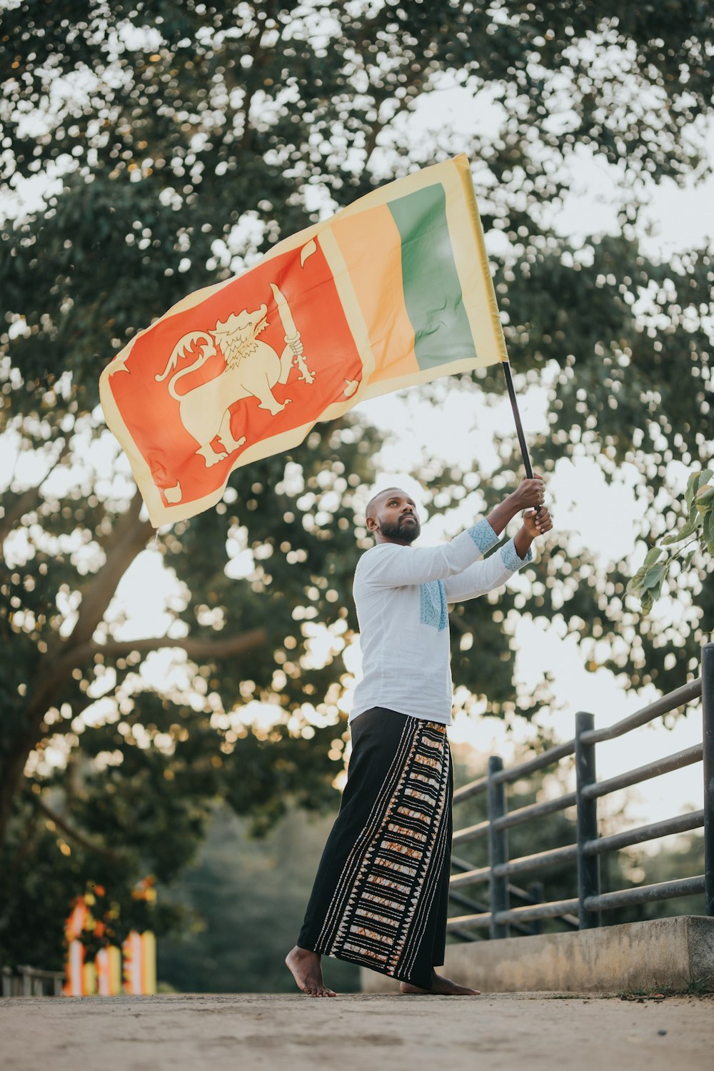 a man holding a flag in front of a fence