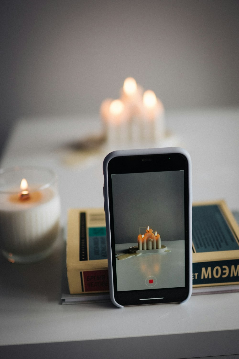 Un teléfono celular sentado encima de una mesa junto a una vela