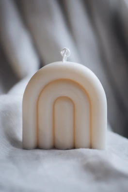 Elegant white candle with delicate shadows cast on a linen cloth.