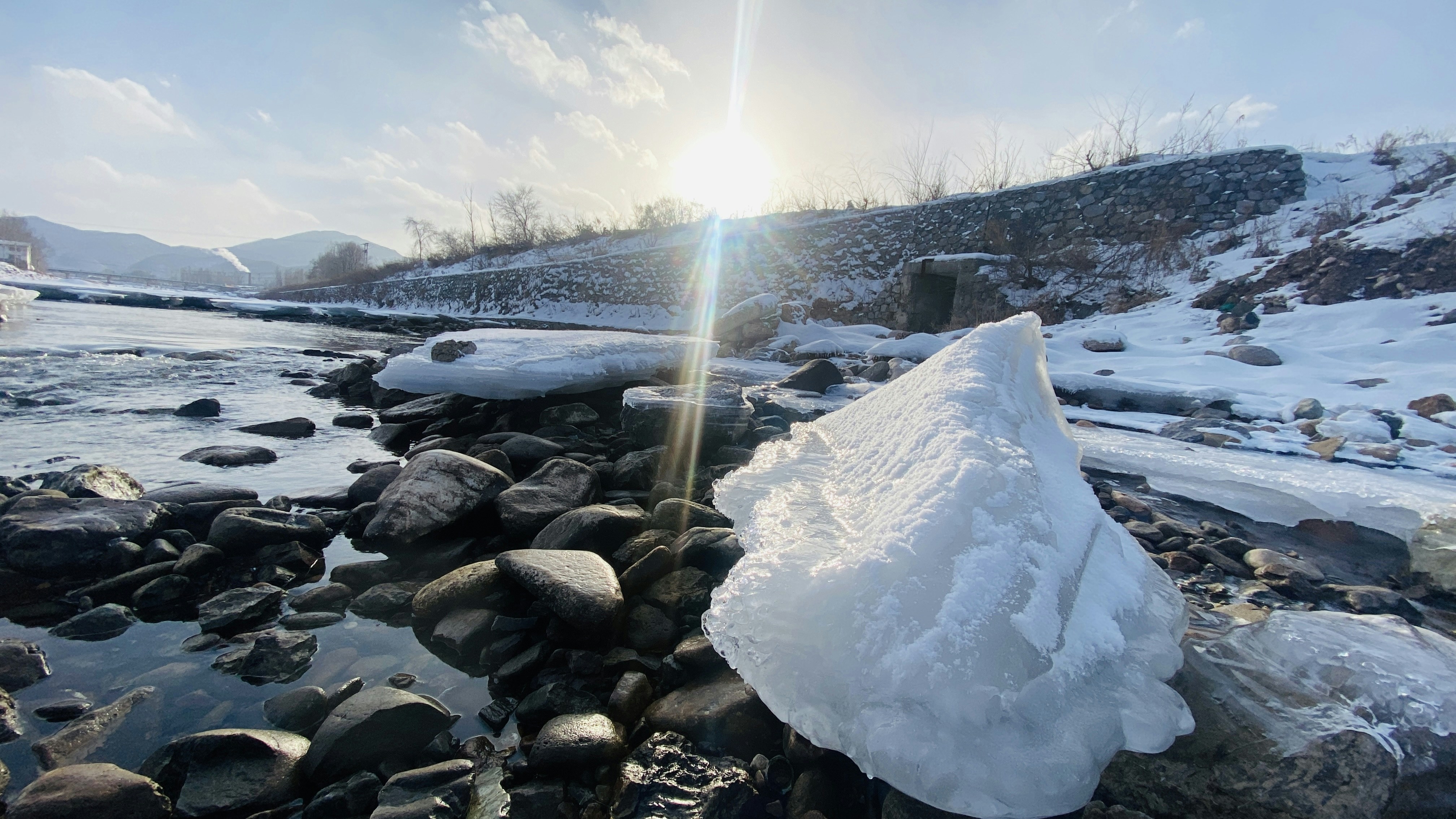 the sun shines brightly over a rocky river