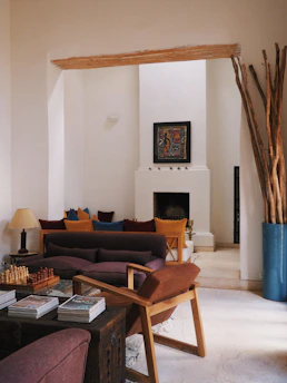 A cozy living room showcasing an eclectic mix of vintage and modern furniture with warm earth tones and vibrant accent colors.