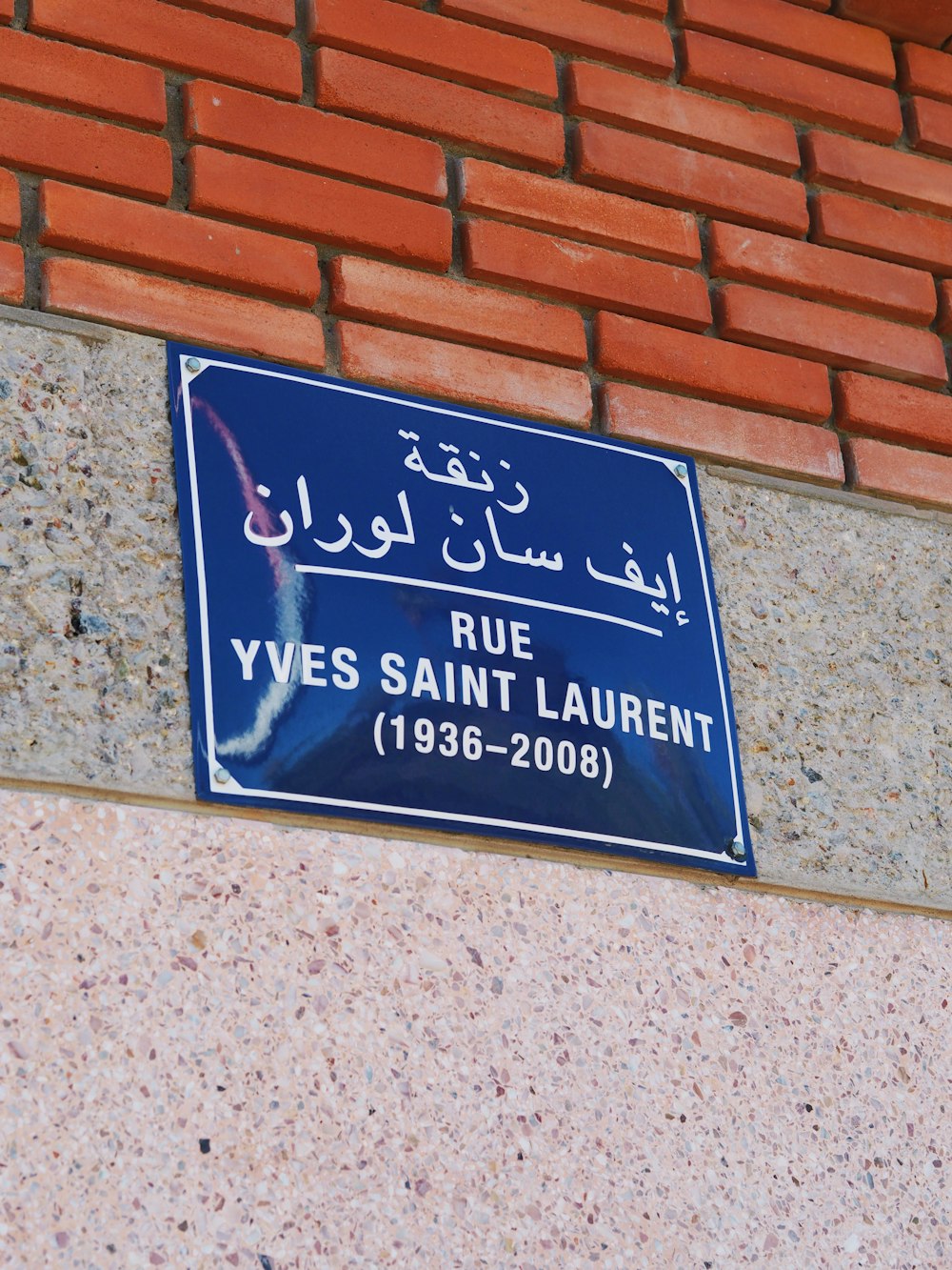 a blue and white sign on a brick wall