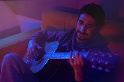 Casual shot of a young woman playing guitar in a cozy, sunlit room.