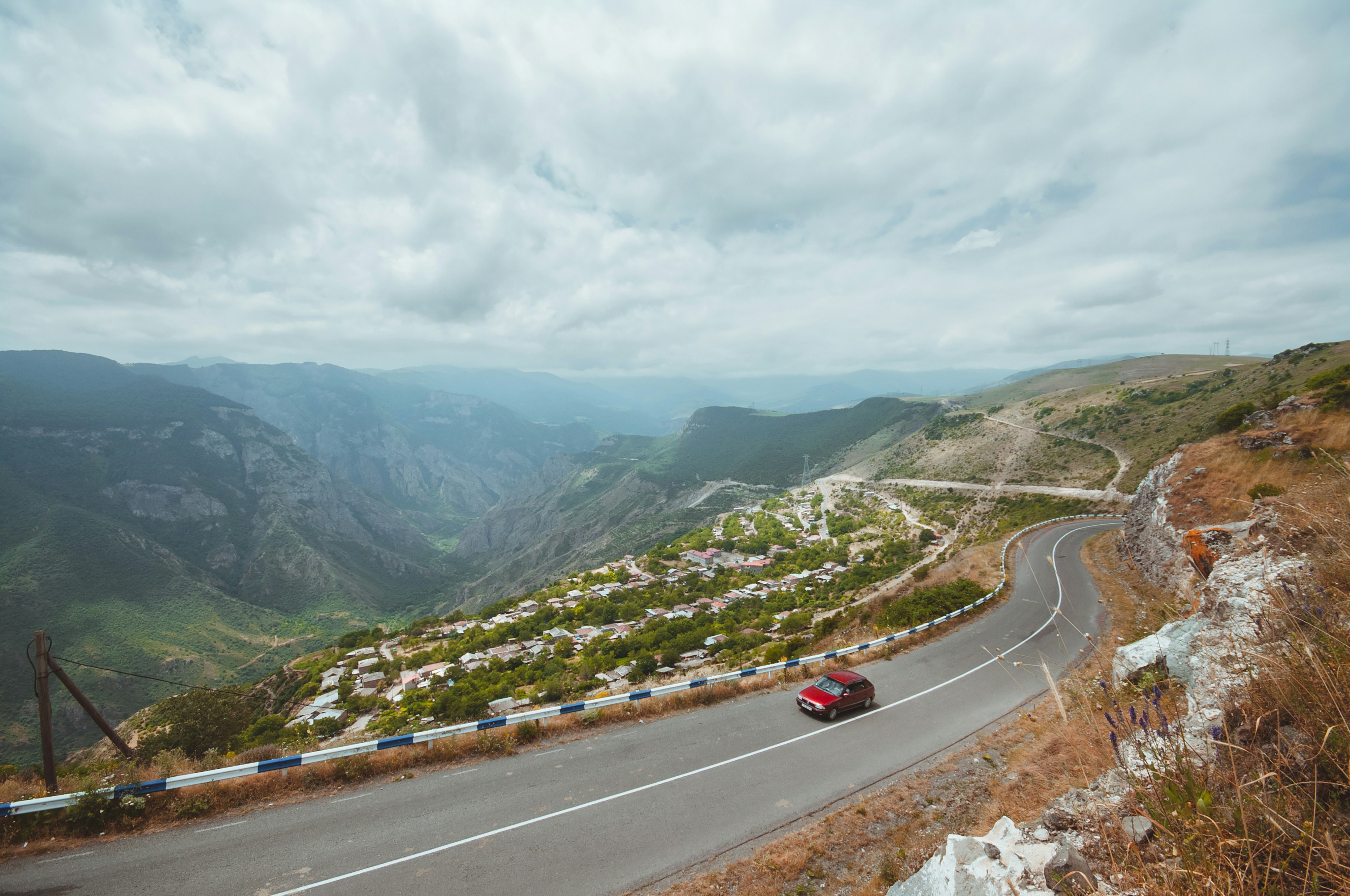 a red car driving down a mountain road, 