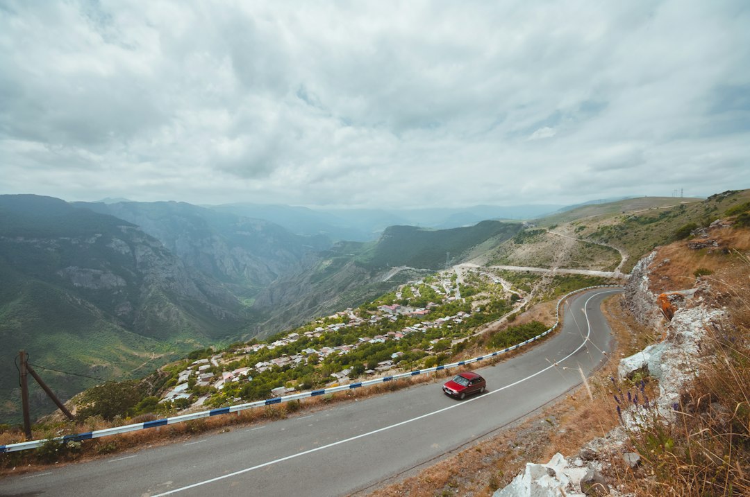 a red car driving down a mountain road,