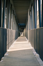 a long walkway with a fence and a clock on the side of it