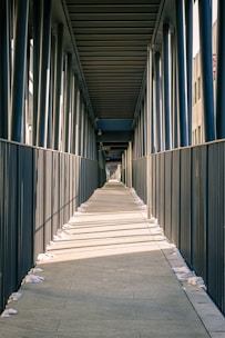 a long walkway with a fence and a clock on the side of it