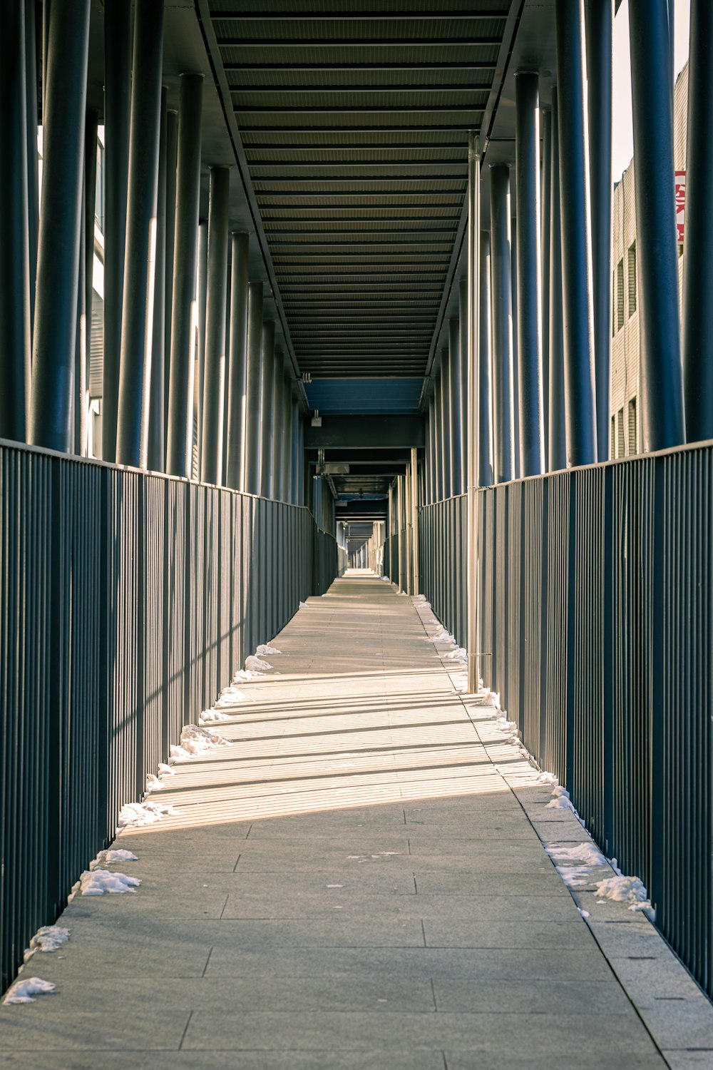 a long walkway with a fence and a clock on the side of it