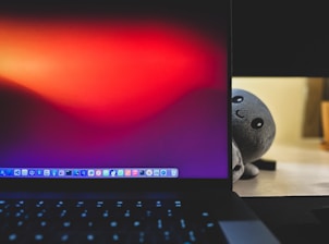 A friendly person using a laptop with multiple tool icons floating around the screen.
