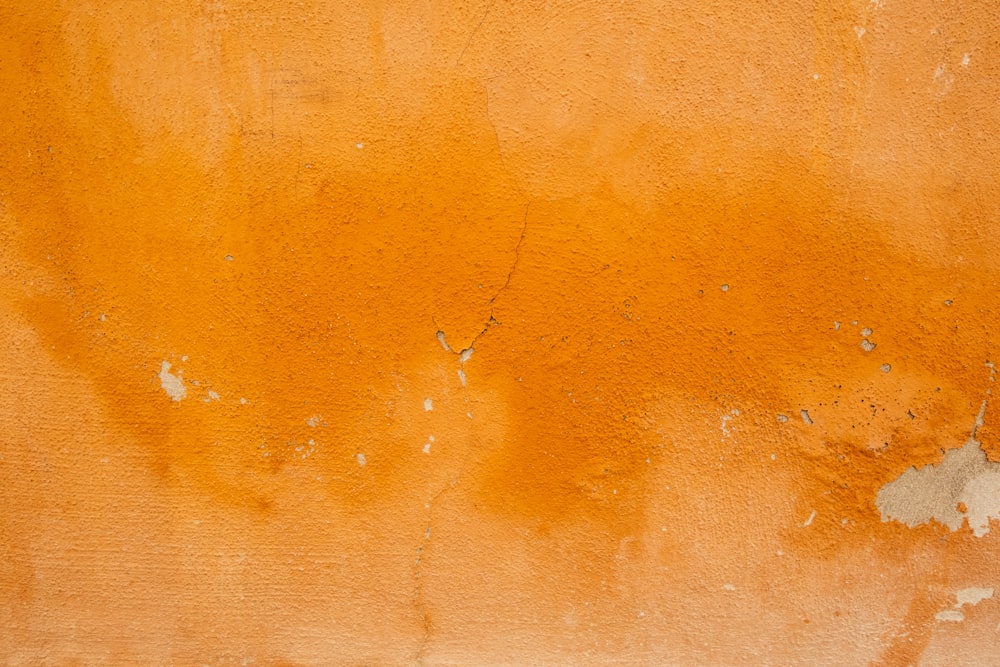 an orange wall with peeling paint on it