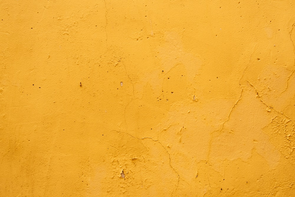 a red fire hydrant sitting next to a yellow wall