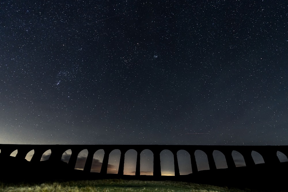 a night sky with stars above a bridge