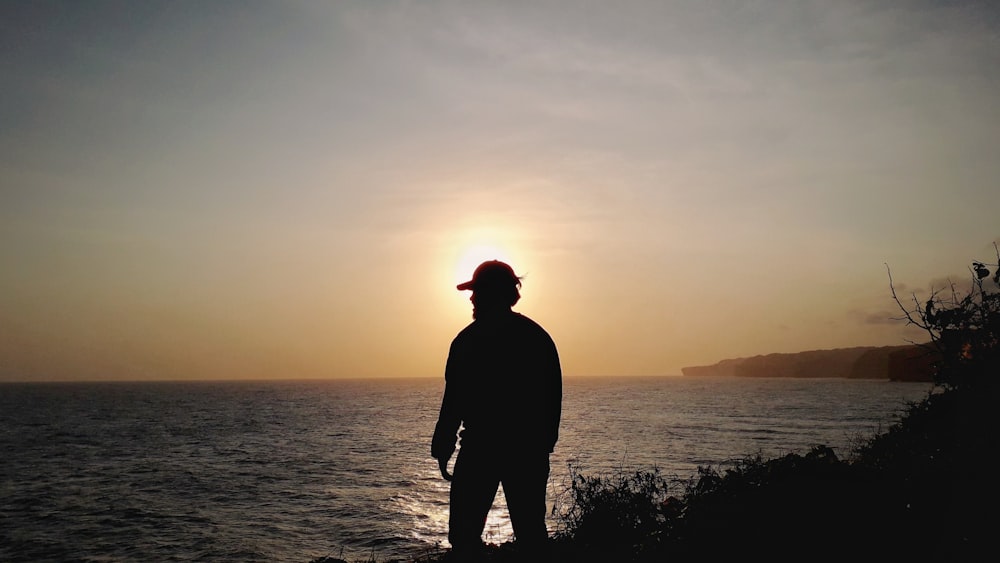 Un uomo in piedi sulla cima di una scogliera vicino all'oceano