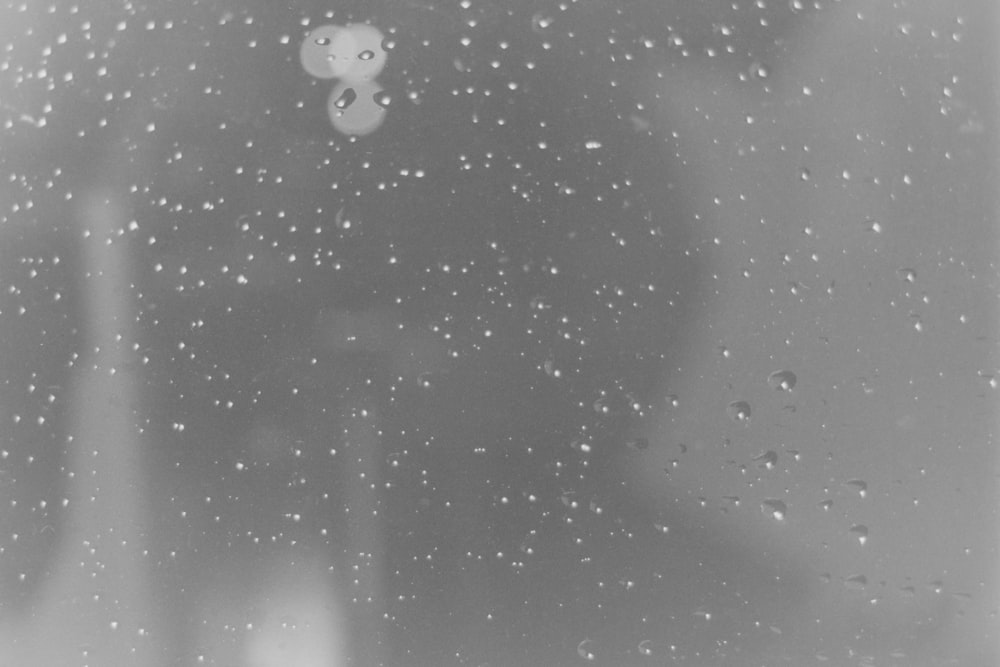 a black and white photo of a window with rain drops