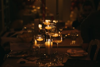 a table topped with lots of glasses filled with candles