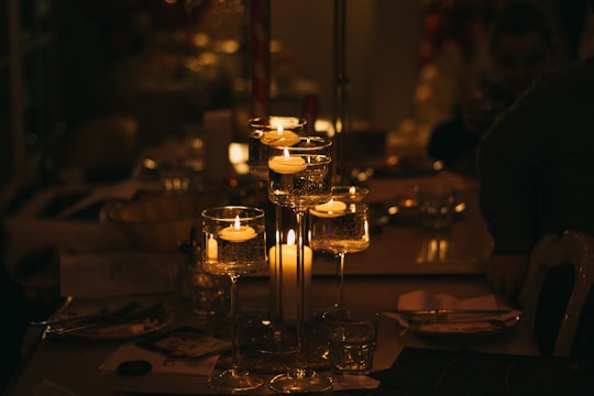 a table topped with lots of glasses filled with candles