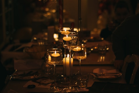 a table topped with lots of glasses filled with candles