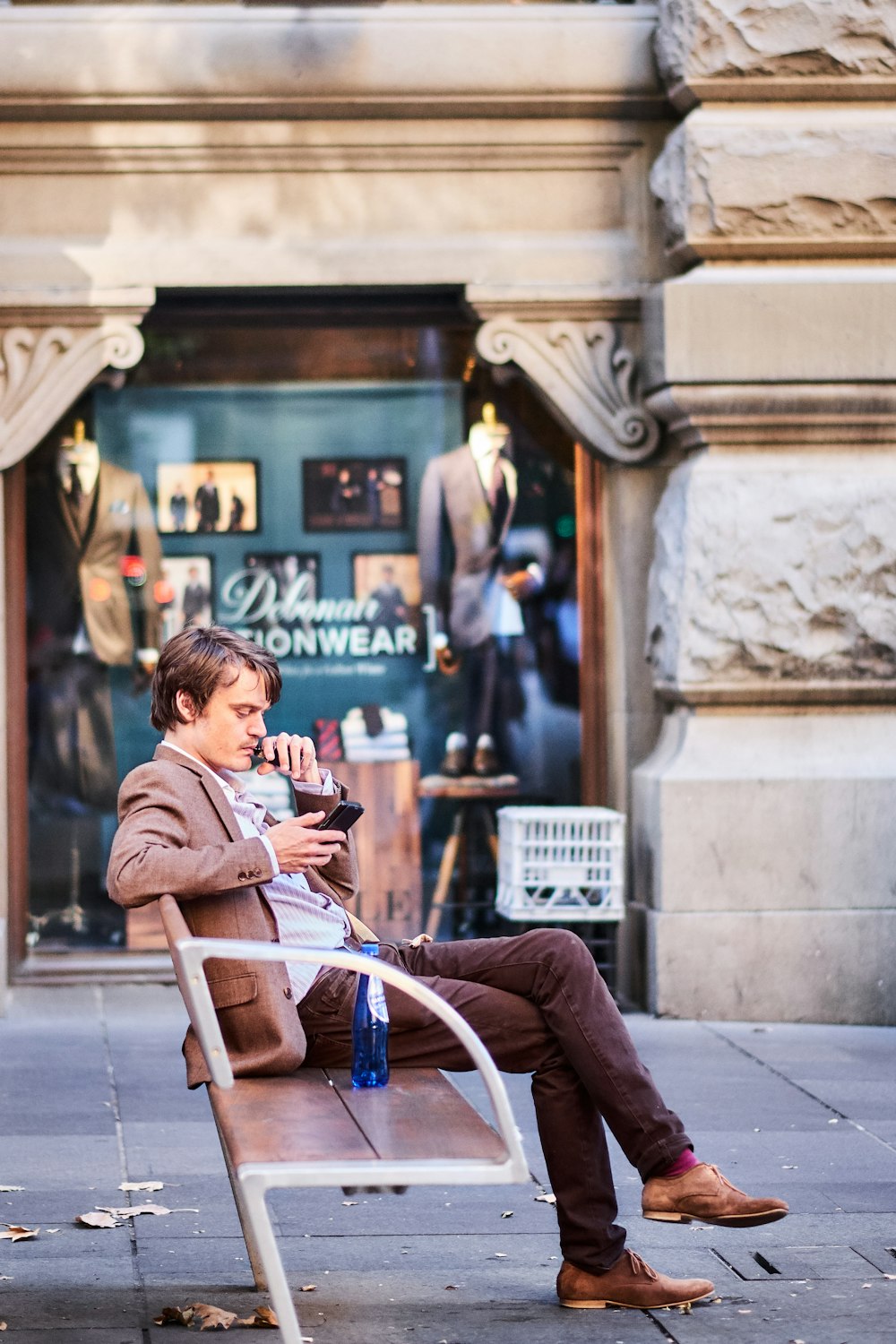 a man sitting on a bench in front of a store
