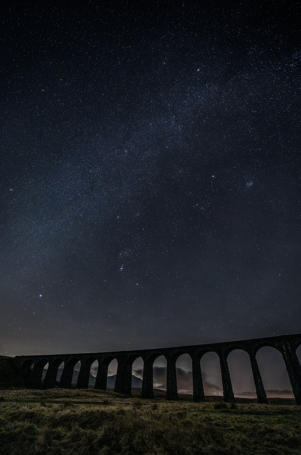 a train traveling over a bridge under a night sky