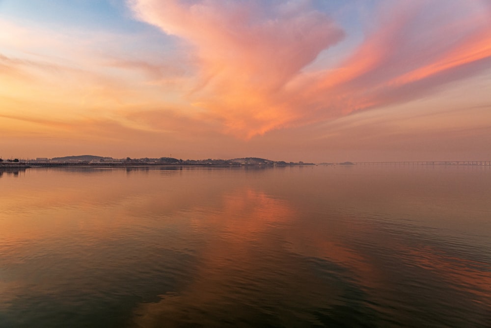 a large body of water with a sky filled with clouds