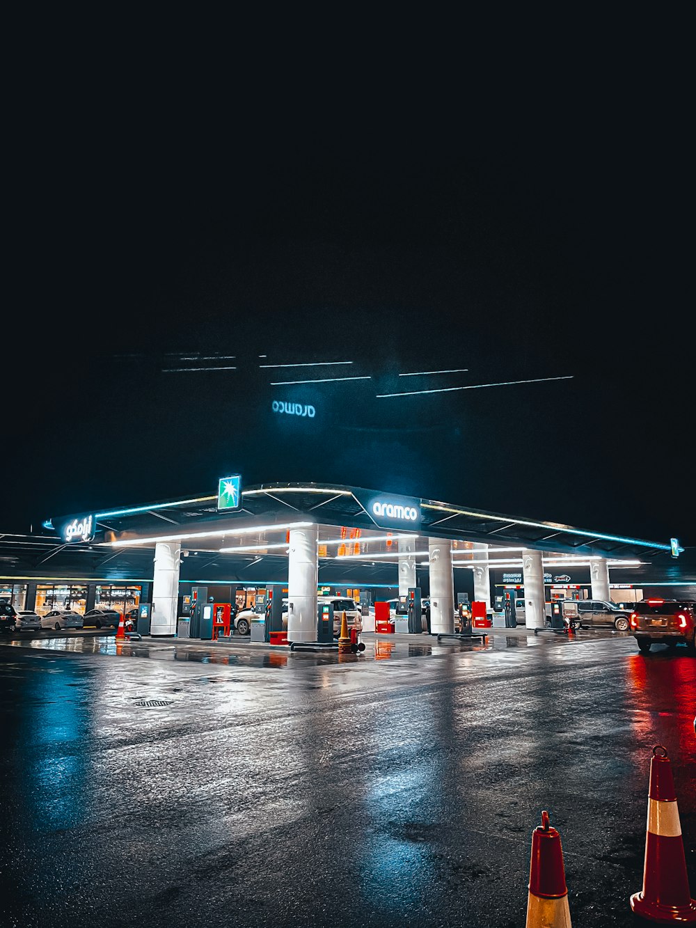 a gas station at night with traffic cones in the foreground