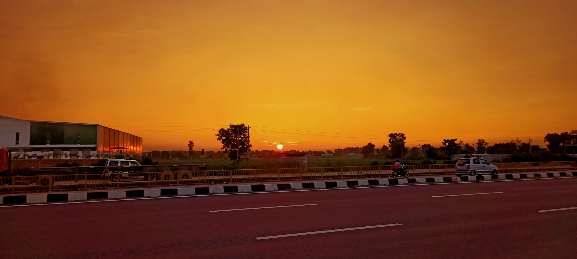 the sun is setting over a highway with cars driving on it
