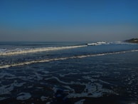 Soft waves rolling onto a white sandy beach under a clear blue sky.