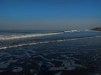 Soft waves rolling onto a white sandy beach under a clear blue sky.